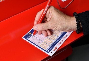  Primo piano della compilazione di una schedina EuroMillions da parte di un giocatore.